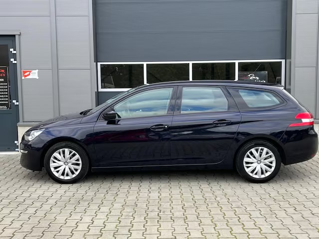 Een donkerblauwe Peugeot 308 SW voor het pand