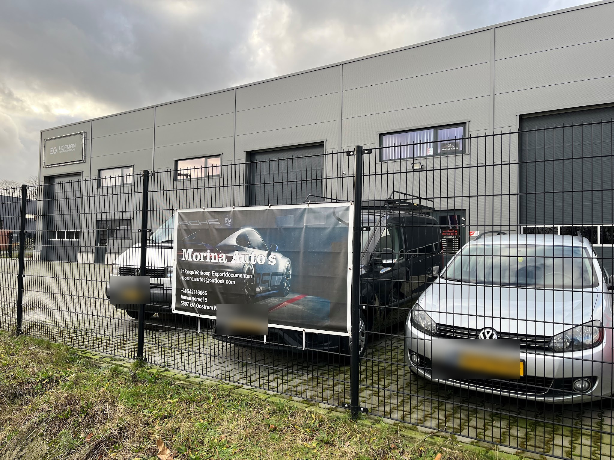 Het terrein van Morina Auto's met het spandoek aan het hek